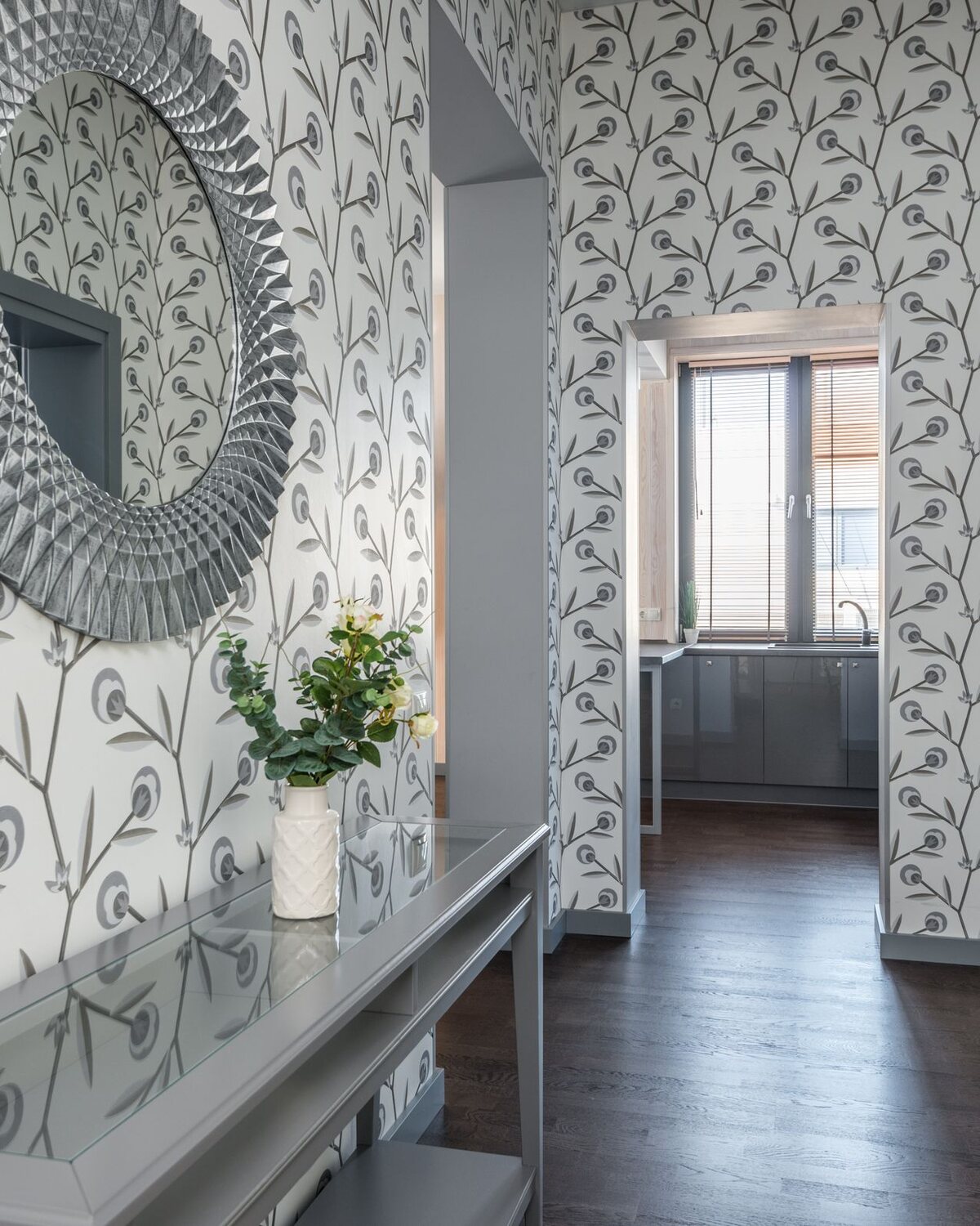 Hallway with peacock-feather botanical wallpaper, a round mirror and a console table